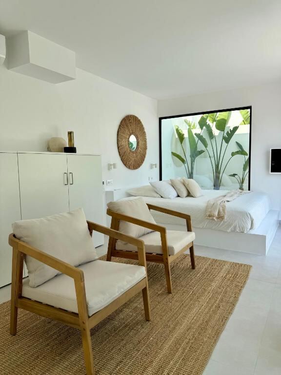 Bedroom with woven mirror, armchairs and garden window