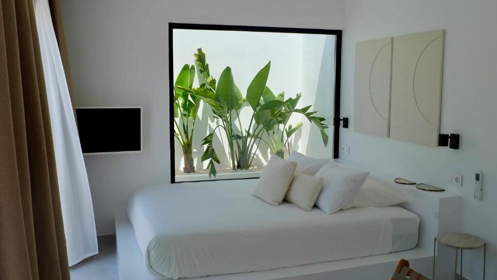 Bed facing a large window with tropical plants
